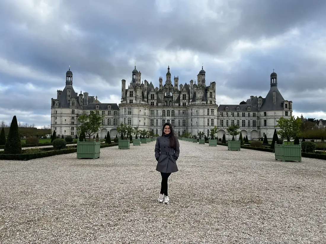 Ariane diante de um castelo francês e seus jardins
