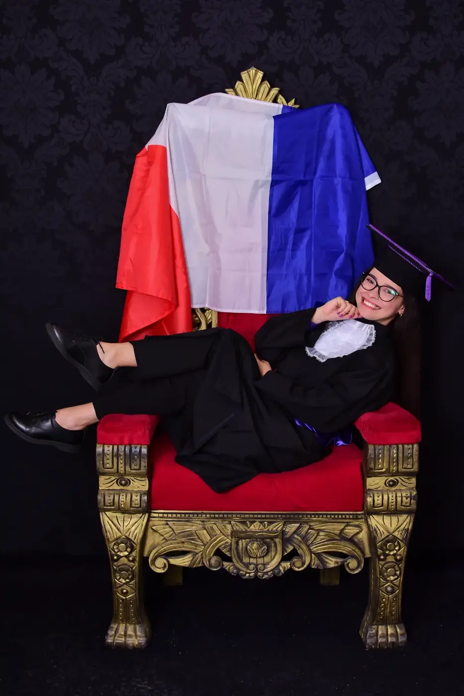 Ariane em uma poltrona com a bandeira francesa ao fundo