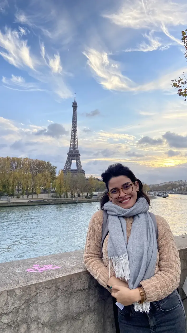 Ariane sorrindo às margens do Sena, com a Torre Eiffel ao fundo